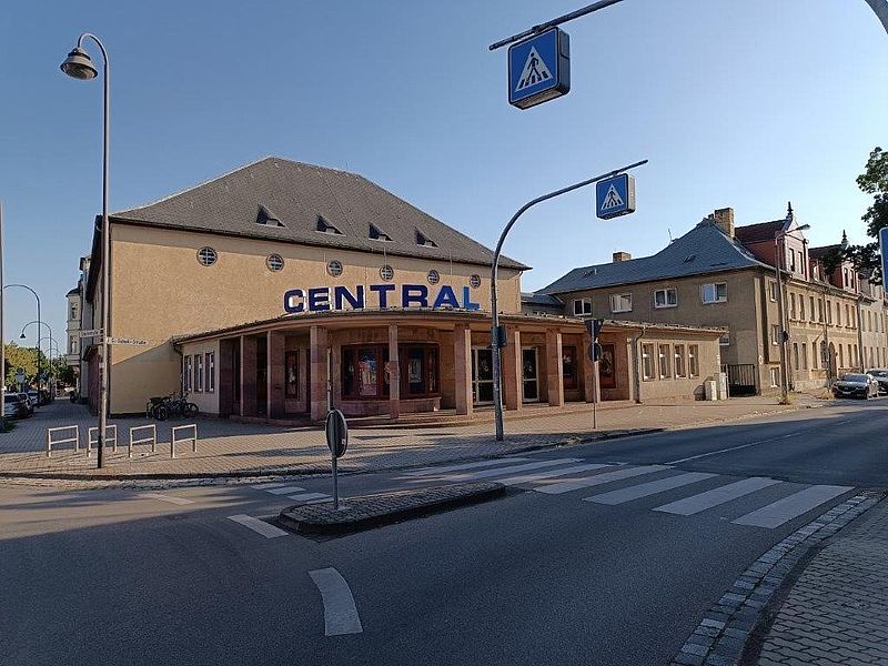 Kino Außenansicht, an einer Straße mit Kreisel und Zebrastreifen, Außenbereich mit Werbung für Filme und barrierefrei